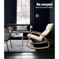 Cream bentwood rocking chair in dark living room with dark sofa, white coffee table and large window, text: Be swayed