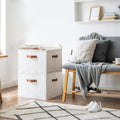 Two stacked cream fabric shoe organizer boxes in living room next to grey sofa and wooden bench