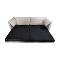 Cream sofa bed in fully extended flat position showing black pull-out mattress on white background