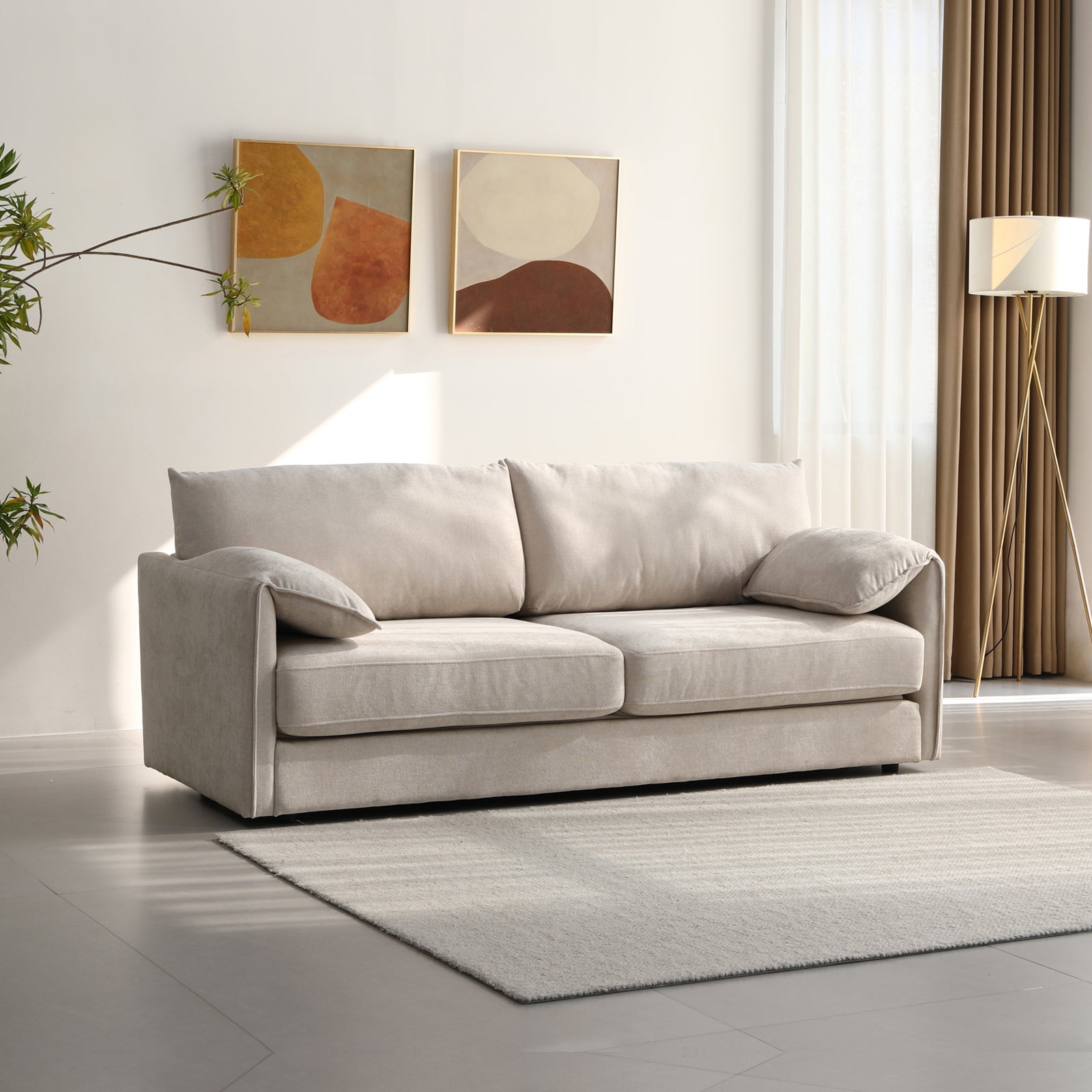 Cream plush sofa bed in lifestyle room with floor lamp and two abstract artworks on wall
