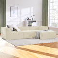 Cream modular sofa with grey cushions in sunlit living room, green curtains, timber floor, patterned throw on ottoman