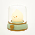 Smiley face raindrop LED lamp in glass dome on mint green base with gold trim and rotary knob on white background