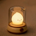 Smiley face raindrop LED lamp in glass dome on cream base glowing warmly on beige carpet in dim room