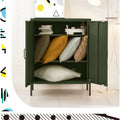 Dark green two-door locker cabinet open with shelves storing coloured cushions, books and a tray