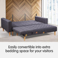 Dark grey L-shape sectional sofa converted to flat bed position in room with wood-panel wall