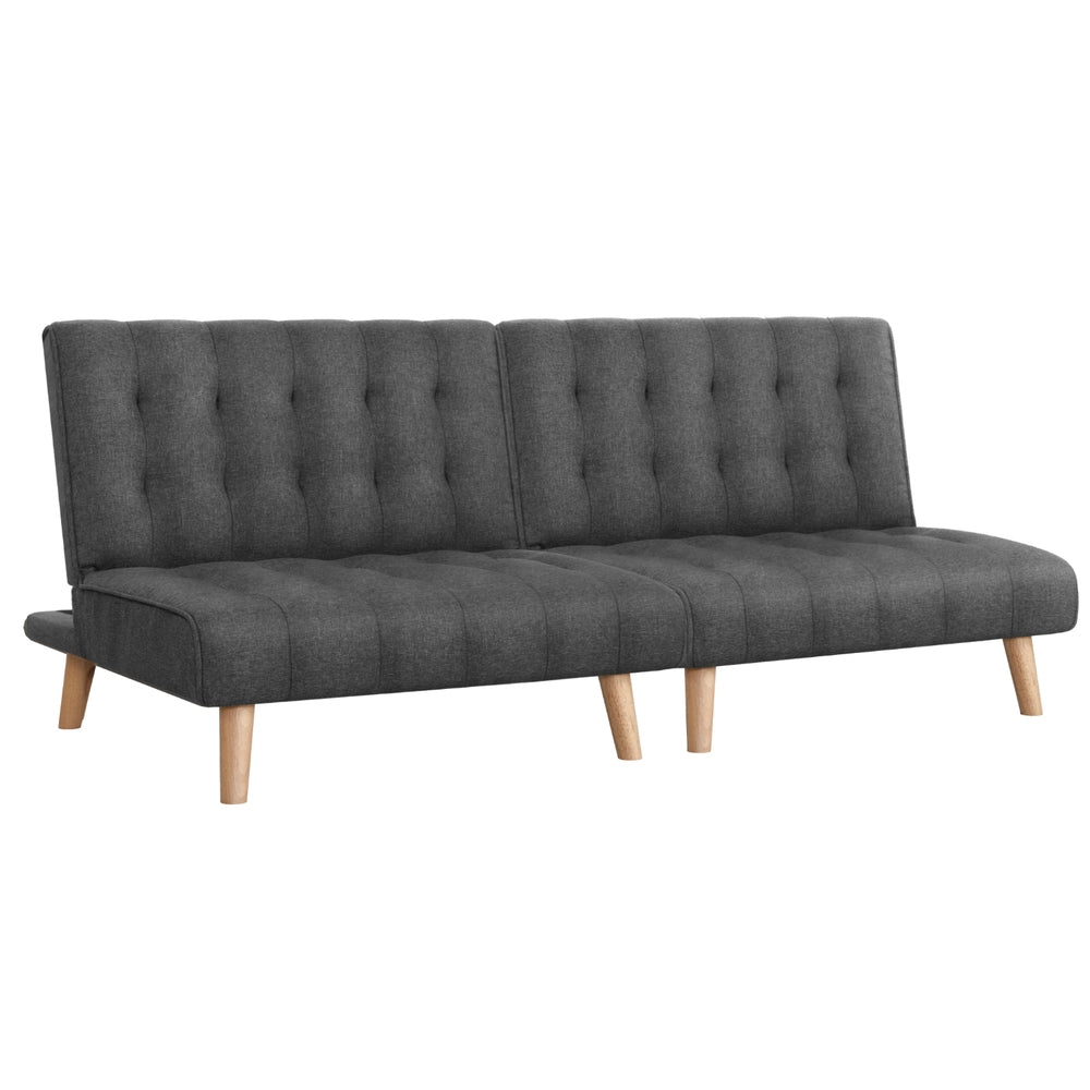 Dark grey tufted armless sofa bed with reclined backrest and wooden legs on white background angle view