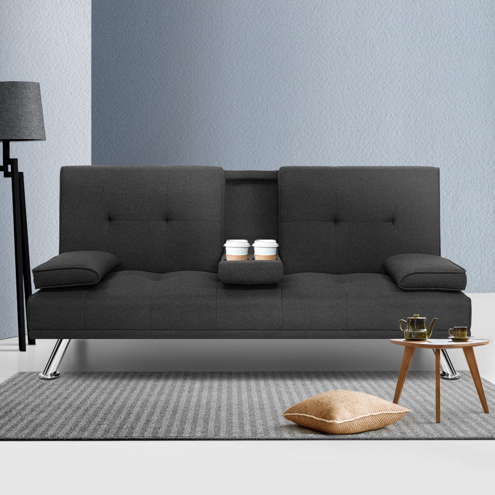 Dark grey fabric sofa bed with cup holder tray open holding two coffee cups in modern living room
