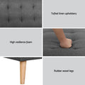 Dark grey tufted sofa bed in flat position in living room with wooden floors and area rug