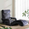 Dark grey velvet floor lounger with adjustable backrest and curved footrest in upright position, white wall lifestyle setting