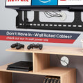 White cable grommet in wall-mounted TV bracket setup gaming controllers and PS4 shelf below in-wall cable routing shown