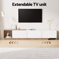 Extendable TV unit in extended position under wall-mounted TV with open left shelf on herringbone floor