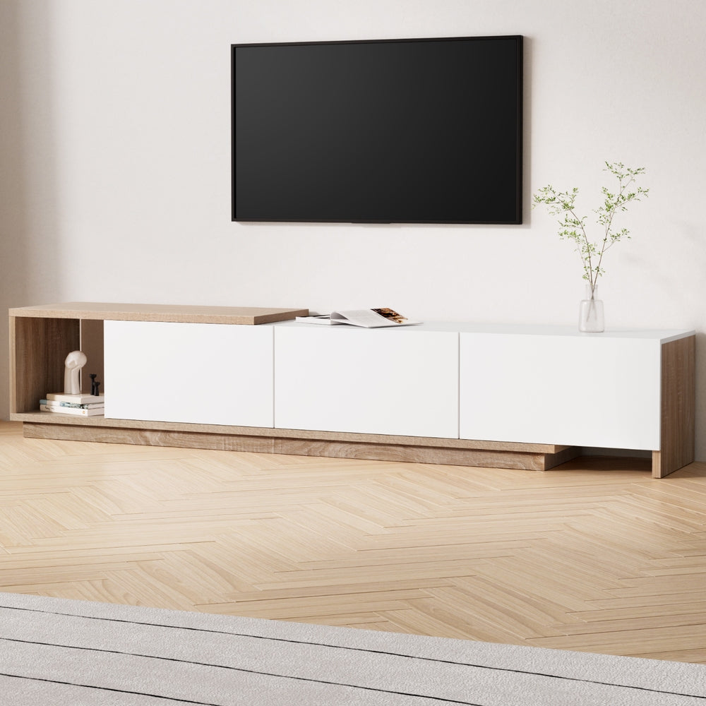 White extendable TV unit with 3 doors and open left shelf on herringbone floor with TV mounted above