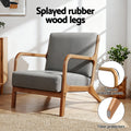 Grey fabric armchair with callouts: splayed rubber wood legs, smooth round corners, floor protectors, in room setting