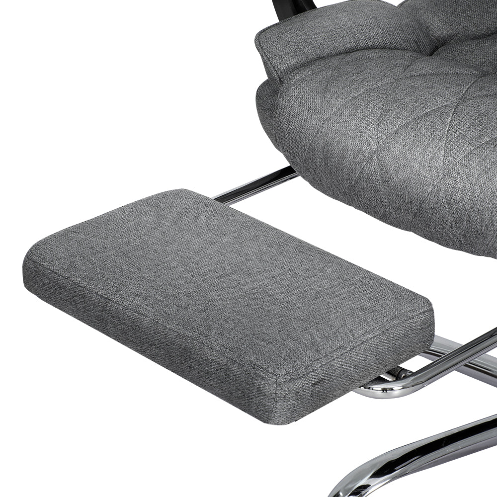 Close-up of grey fabric retractable footrest pad with chrome support arm from executive office chair on white background