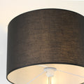 Close-up of black fabric drum shade on dual-shade floor lamp showing linen texture and lit interior with nickel fitting