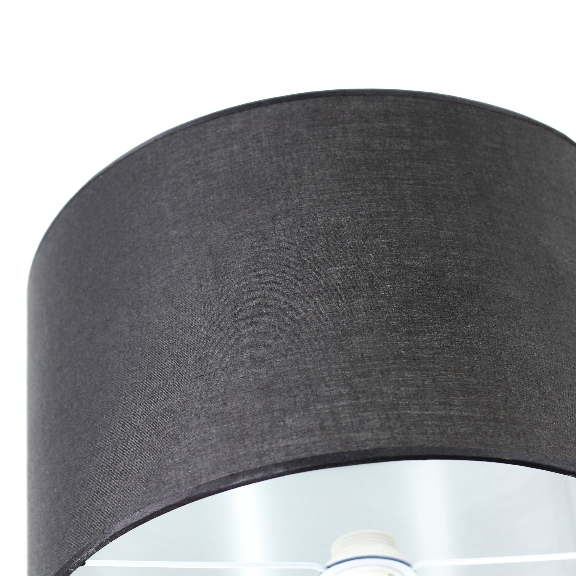Angled top close-up of black fabric drum shade on floor lamp with silver chrome fitting visible at base of shade