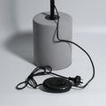 Grey concrete cylinder lamp base with black cord, oval foot switch and Australian three-pin plug