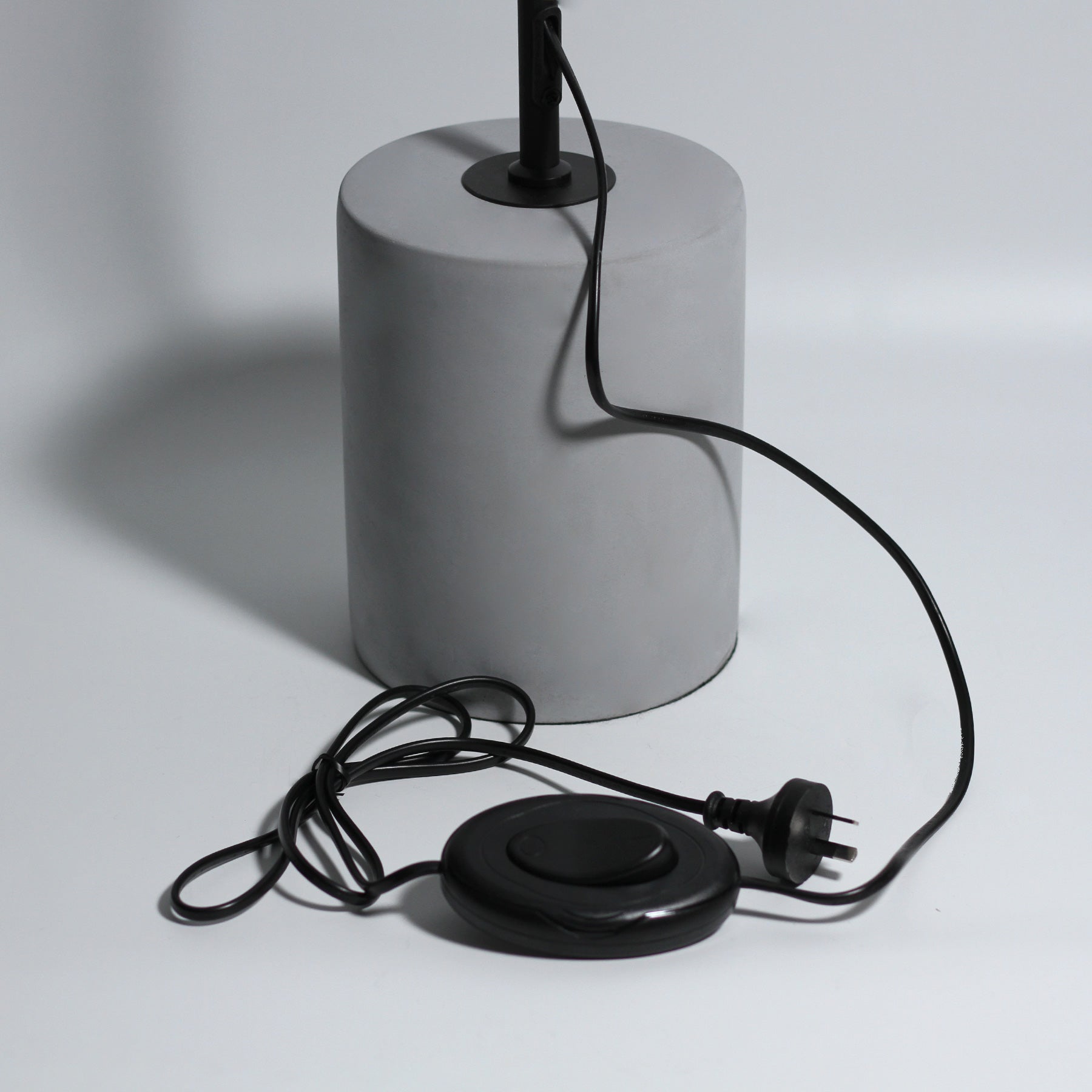 Grey concrete cylinder lamp base with black cord, oval foot switch and Australian three-pin plug