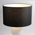 Close-up of black fabric drum shade showing linen texture and cream interior lining at rim, white frosted glass ball below