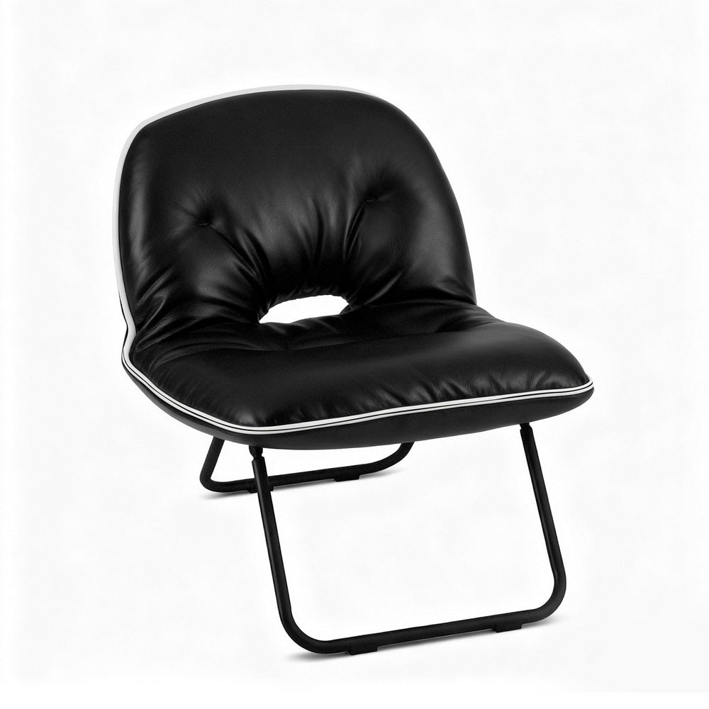 Black foldable floor chair with tufted back and white piping in room setting by window, inset shows folded bag form