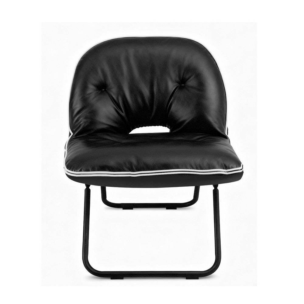 Black foldable floor chair with tufted back, centre cutout and white piping, front view on white background