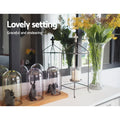 White console table top with glass cloches, animal figurines, cage lantern and flower vase; text 