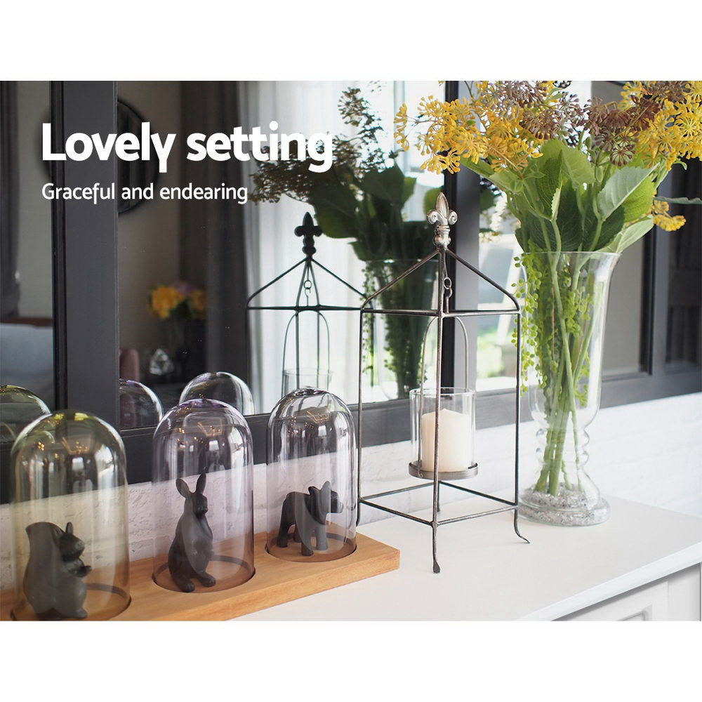 White console table top with glass cloches, animal figurines, cage lantern and flower vase; text "Lovely setting"