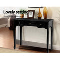 Black French provincial console against wall styled with amber vases, photo frame and plant; text 
