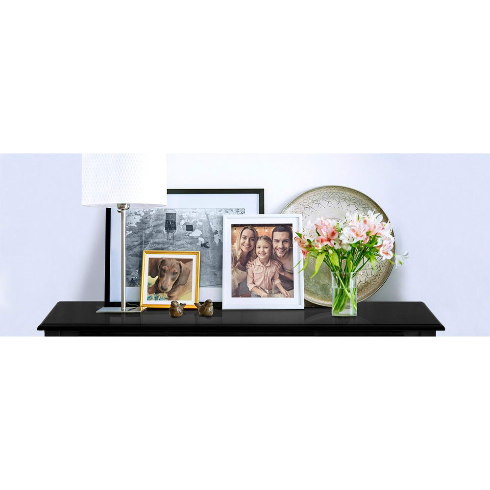 Black console table top surface styled with photo frames, lamp, decorative plate and pink flower vase