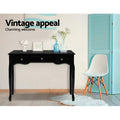 Black French provincial console in room with blue vases and Eames chair; teal screen beside; text 