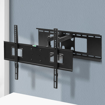 Full-motion TV wall bracket extended arms mounted on blue-grey corner wall with spirit level on TV plate