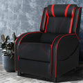 Black and red gaming recliner with red piping and neck roll headrest against concrete textured wall, lifestyle setting