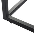 Close-up detail of black powder-coated metal table foot and frame junction with small rubber floor protector pad on white