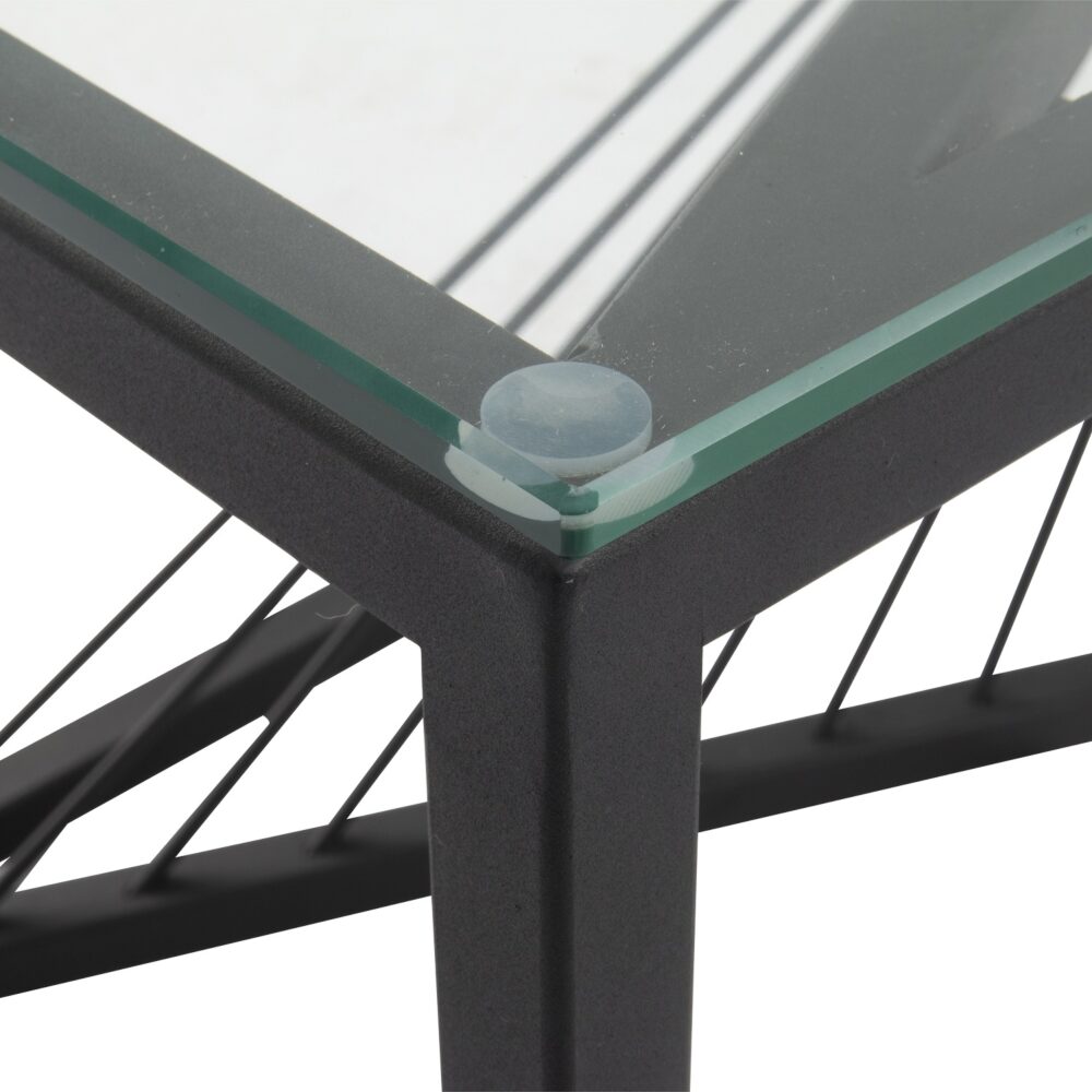Close-up detail of coffee table corner showing clear glass top with green-tinted edge resting on black metal frame with
