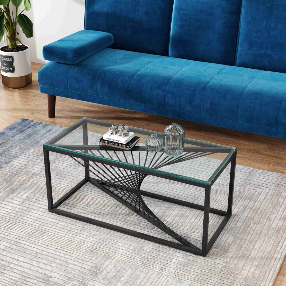Rectangular glass-top coffee table with black metal starburst base, angled view with blue sofa, potted plant and decorative
