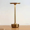 Gold slim-stem table lamp with flat disc shade on wooden surface, knurled stem and USB-C port on circular base