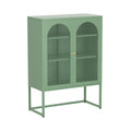 Sage green metal sideboard with two arched mesh doors, gold round knobs and rectangular metal frame base, angle view on white
