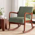 Green corduroy rocking chair with dark wood frame on circular rug in bright room, side table with plant vase beside
