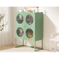 Green metal cabinet with circular glass doors filled with kitchenware, styled in a bright room with white curtains