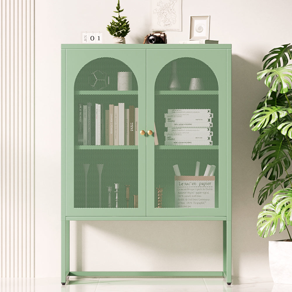 Sage green metal sideboard with arched mesh doors in room, books and stationery visible inside, decorative items on top