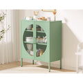 Sage green metal sideboard in light room with dishes and teapot visible through mesh doors, kitchen items on top