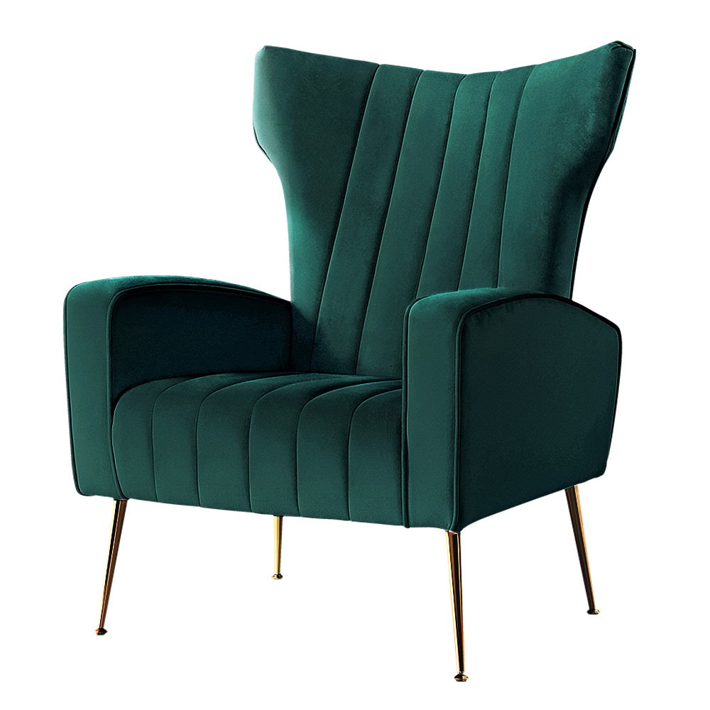 Green velvet wingback armchair with vertical channel tufting and gold metal legs, angle view on white background