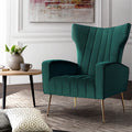 Dark green velvet wingback armchair with gold legs on textured rug beside round wooden side table, panelled wall
