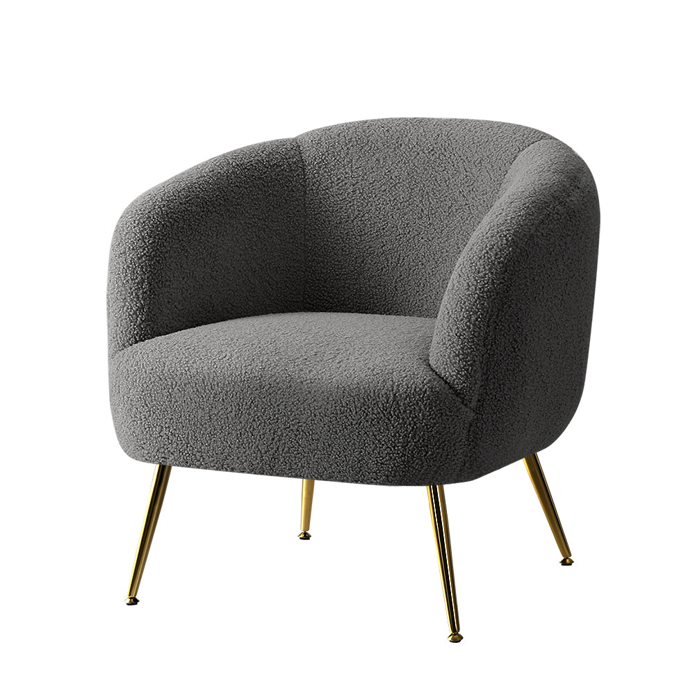 Grey boucle armchair with curved barrel back and gold metal legs, three-quarter angle view on white background