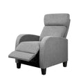 Grey boucle armchair with thick column legs and open back, beside small round table with coffee cup, fireplace background