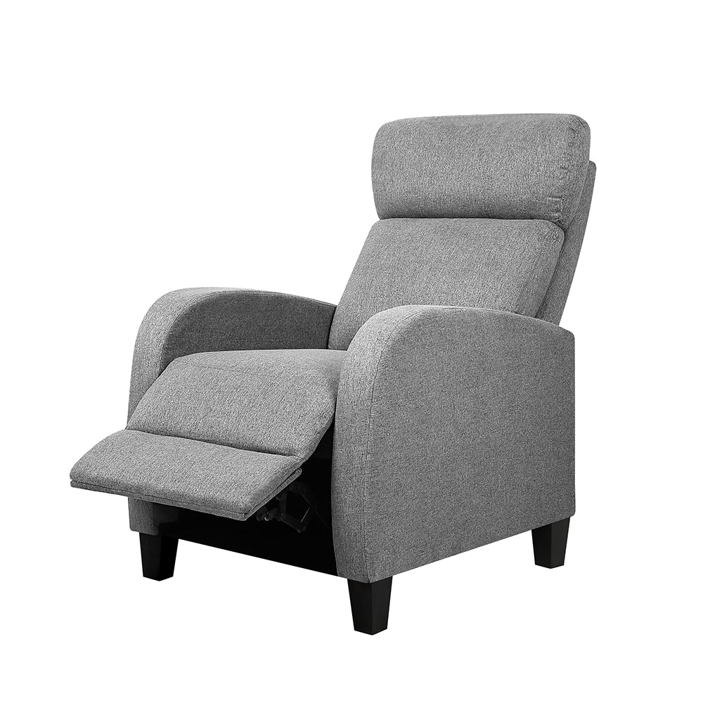 Grey boucle armchair with thick column legs and open back, beside small round table with coffee cup, fireplace background