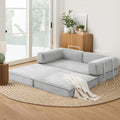 Grey corduroy folding sofa bed fully extended on jute rug in living room; chrome arm handles and white throw blanket