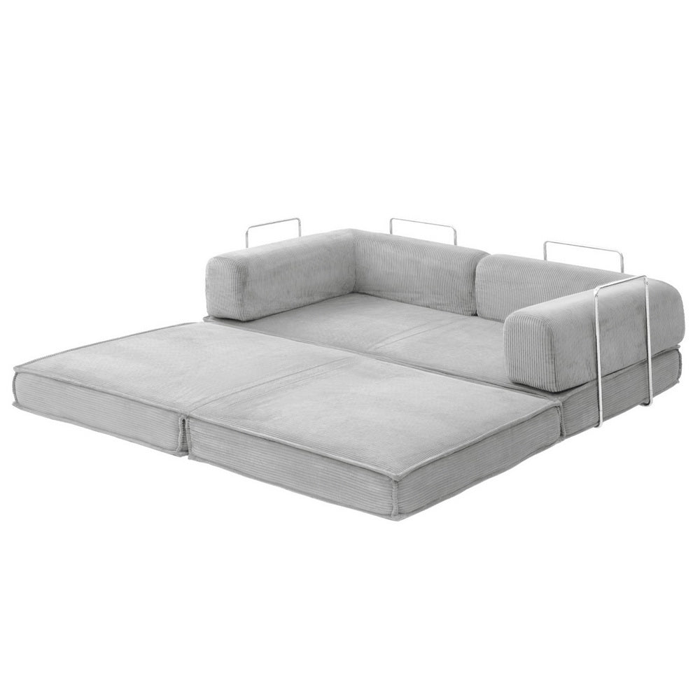 Grey corduroy folding sofa bed fully extended on jute rug in living room; chrome arm handles and white throw blanket