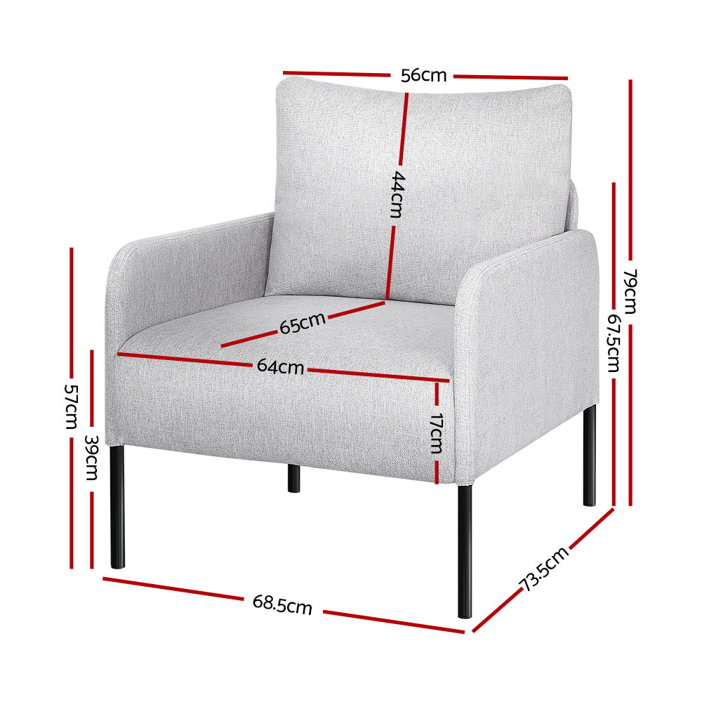 Light grey fabric armchair with black metal legs in living room with folding screen, side table with flowers and magazine