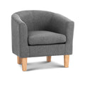 Grey fabric barrel armchair with rounded back and natural wood legs, angle view on white background